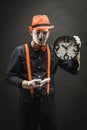 Scary clown pantomime with a clock in his hands, on a dark background Royalty Free Stock Photo