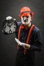 Scary clown pantomime with a clock in his hands, on a dark background Royalty Free Stock Photo