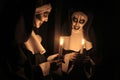 Scary devilish nun with burning candle near mirror on black background. Halloween party look Royalty Free Stock Photo