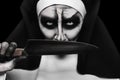 Scary devilish nun with knife on black background, closeup. Halloween party look