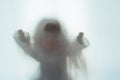 A scary edit of an old doll holding its hands up, shot through a semi transparent material. Creating a textured, blurred, still