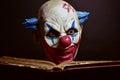 Scary evil clown reading a book Royalty Free Stock Photo