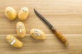 Scary face potatoes and knife on wooden cutting board Royalty Free Stock Photo