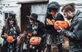 Scary family,mother,father,daughters celebrating halloween.Pumpkins jack-o-lantern.Terrifying black skull face makeup,stylish