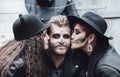 Scary family, mother, father, daughters celebrating halloween. Terrifying black skull half-face makeup and witch