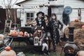 Scary family, mother, father, daughters celebrating halloween. Terrifying black skull half-face makeup and witch