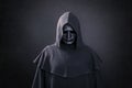 Scary figure with mask in hooded cloak in the dark Royalty Free Stock Photo