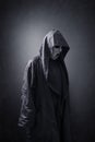 Scary figure with mask in hooded cloak