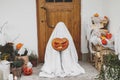 Scary ghost holding Jack o lantern at front of house with spiders web, pumpkin and candle. Trick or treat! Spooky halloween Royalty Free Stock Photo