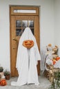 Scary ghost holding Jack o lantern at front of house with spiders web, pumpkin and candle. Trick or treat! Spooky halloween Royalty Free Stock Photo