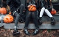 Scary girls, sisters, friends celebrating halloween.Treak or treat game.Pumpkins.Sitting on porch steps.Bags with sweets in hands.