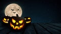 Scary glowing pumpkins on a wooden table on a background of a full moon with bats at night. Halloween and holiday wallpaper Royalty Free Stock Photo
