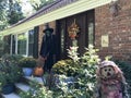 The scary green face witch with black outfit and pointed hat and scarecrow in front of the house