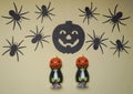 Scary Halloween figurines stand on a light background close-up, behind hangs terrible black pumpkin and spider Royalty Free Stock Photo