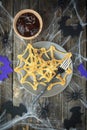 Scary Halloween food pancakes spider web with spiders in a plate on a spooky wooden table. Halloween concept. View from above