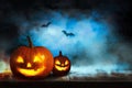 Scary Jack O Lantern pumpkins and flying bats in forest on Halloween. Space for text Royalty Free Stock Photo