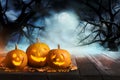 Scary Jack O Lantern pumpkins surrounded by mystical mist under moon on Halloween. Space for text Royalty Free Stock Photo