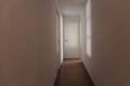 Scary light-walled hallway with a closed door illuminated by the dim shadow of a window, copy space Royalty Free Stock Photo