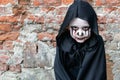 Scary little girl in a little zombie costume looks frighteningly at the camera against a brick wall. copy space. zombie Apo. Royalty Free Stock Photo