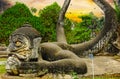 Scary mystic mythological hindu stone creature sculpture in green garden, spectactular sunset sky - Buddha Park Wat Xieng Khuan