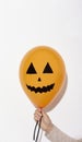 Scary orange Halloween balloon in woman hand on white