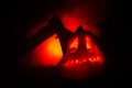 Scary orange pumpkin with carved eyes and a smile with burning candles and an ax on a dark background with fire sky. For the Hallo Royalty Free Stock Photo