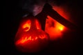 Scary orange pumpkin with carved eyes and a smile with burning candles and an ax on a dark background with fire sky. For the Hallo Royalty Free Stock Photo
