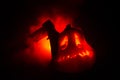 Scary orange pumpkin with carved eyes and a smile with burning candles and an ax on a dark background with fire sky. For the Hallo Royalty Free Stock Photo