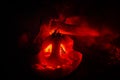 Scary orange pumpkin with carved eyes and a smile with burning candles and an ax on a dark background with fire sky. For the Hallo Royalty Free Stock Photo