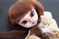 Scary plastic redhead doll with scarf lying on dark gray background