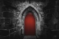 Scary pointy red wooden door in an old and wet stone wall building with cross, skull and bones at both sides. Concept mystery,