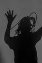 Scary silhouette of crying person with clotted hair, terrifying shadow on dark wall or behind mirror. Horror, nightmare