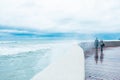 Scary Stormy Waves with Big Sea Wave Splashing Over pier Road at cloudy autumn rainy day. High wave is breaking on the pier. Two Royalty Free Stock Photo