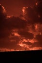 Scary sunset, with red sky and clouds, after storm. Power pylons and industrial fences in devastated landscape. B Evil environment