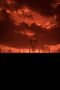 Scary sunset, with red sky and clouds, after storm. Power pylons and industrial fences in devastated landscape. B Evil environment Royalty Free Stock Photo