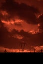 Scary sunset, with red sky and clouds, after storm. Power pylons and industrial fences in devastated landscape. B Evil environment Royalty Free Stock Photo