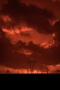 Scary sunset, with red sky and clouds, after storm. Power pylons and industrial fences in devastated landscape. B Evil environment