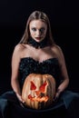 Vampire girl in black gothic dress holding carved Halloween pumpkin with candles isolated on black Royalty Free Stock Photo
