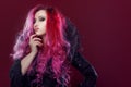 Scary witch with red hair performs magic on a pink background. Halloween, horror theme. Royalty Free Stock Photo