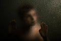 Scary Young Boy Leaning Against a Textured Glass