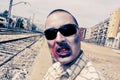 Scary zombie with sunglasses at abandoned railroad tracks, with