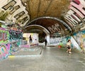 Scateboarders under London Railway Arch covered in Graffiti.