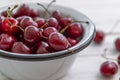 Scattered berries of ripe cherries on a light wooden background and in a bowl. Side view. Seasonal Vitamins Royalty Free Stock Photo