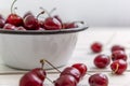 Scattered berries of ripe cherries on a light wooden background and in a bowl. Side view. Seasonal Vitamins Royalty Free Stock Photo