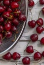 Scattered berries of ripe cherries on a light wooden background and in a bowl. Top view. Seasonal Vitamins. Vertical Royalty Free Stock Photo