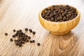 Scattered black pepper, bowl with peppercorn on wooden table Royalty Free Stock Photo