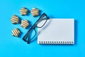 Scattered candies near optical glasses in black plastic frame and blank notepad lies on blue desk