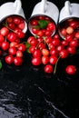 Scattered cherry from enamel cups. Cherries in iron cup on black background. Healthy, summer fruit. Cherries. Three. Close up. Royalty Free Stock Photo