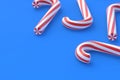 Scattered Christmas canes, candy with red stripes on blue background