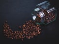 scattered coffee beans from a glass jar on a black background. coffee mood. Royalty Free Stock Photo